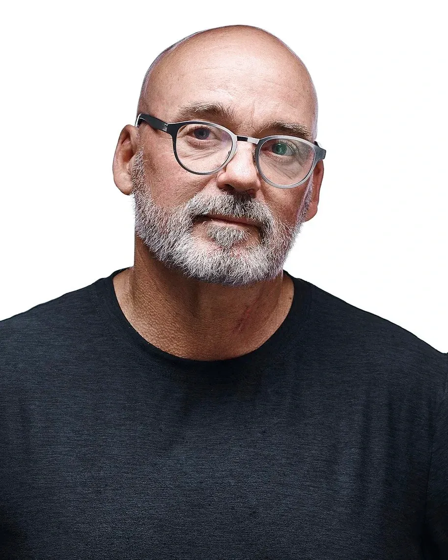 A bald man with a gray beard and glasses on a white background