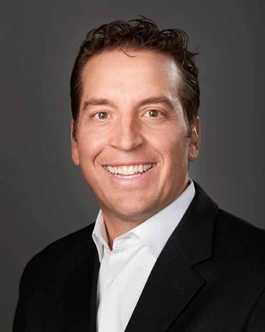 Headshot of a man with brown hair in a dark suit